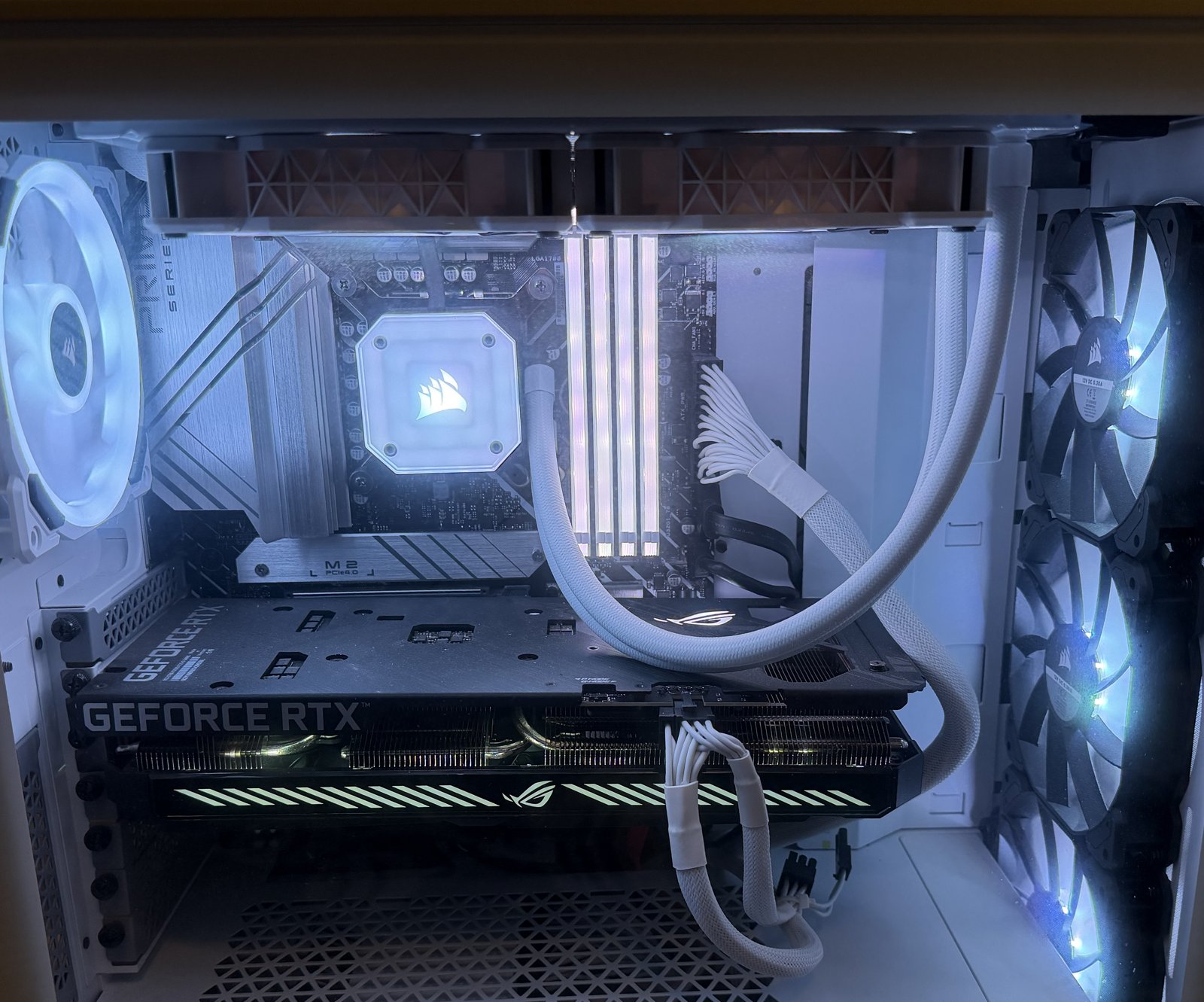 Close-up inside a custom-built PC showing a GeForce RTX graphics card, AIO liquid cooler, and clean white-sleeved cable management